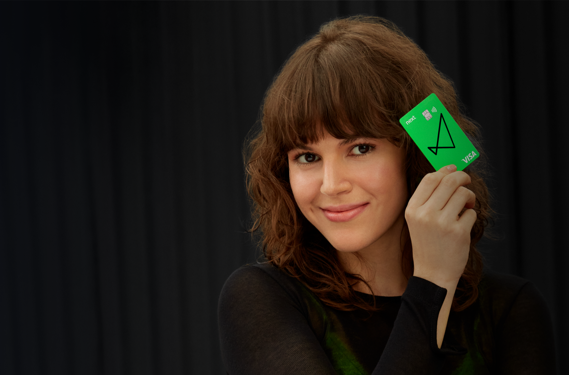 Fotografia da entrada do prédio next mostrando o térreo, com o logo do banco em primeiro plano.